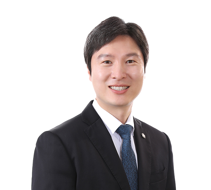 김해영 변호사가 웃으며 까만 정장과 파란색 넥타이를 매고 국회의원 뱃지를 달고 옆으로 비스듬히 서있는 상반신